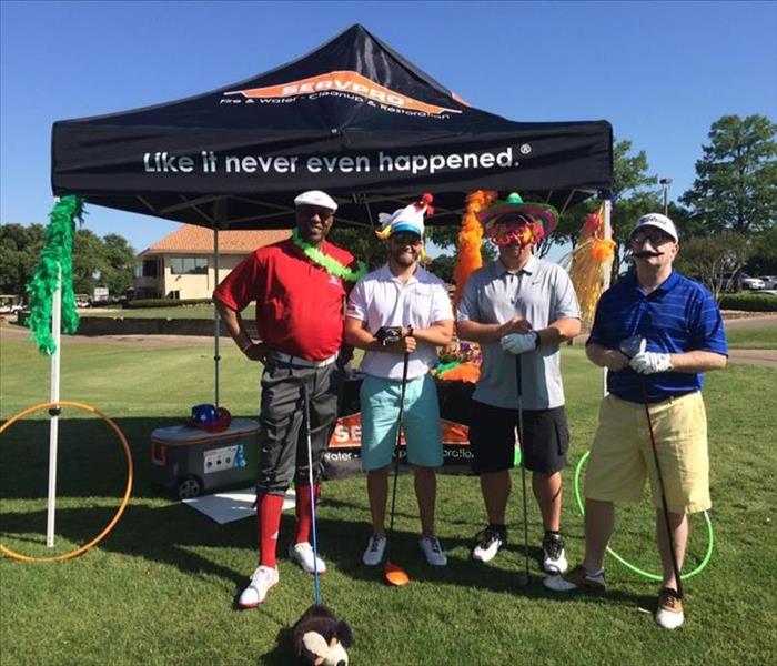 golfers standing next to the SERVPRO tent